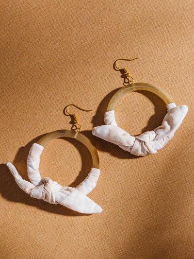 Horn hoop earring with canvas-like cloth wrapped around and tied in a bow.