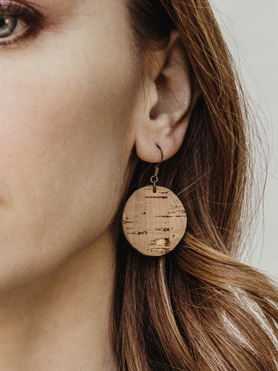 Circular cork textured earrings on a female model with long brown hair.