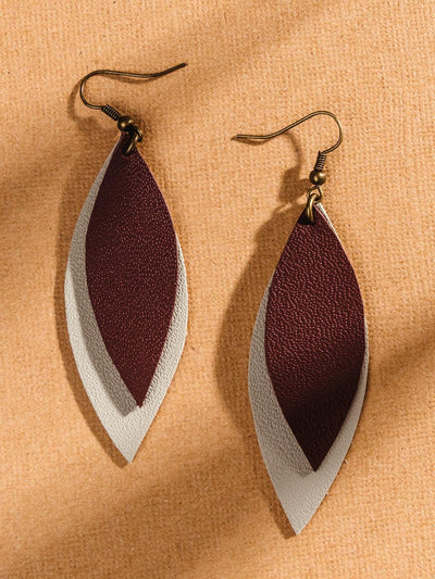 On a tan surface leather leather shape earrings with two layers one brown and one light grey. 