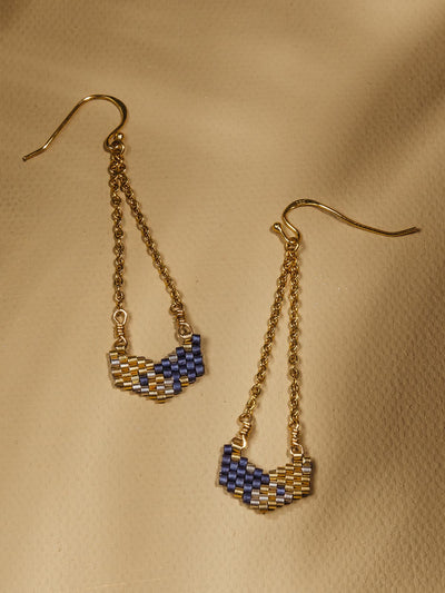 Gold and Blue earrings with beaded pendants on a warm backgroud 