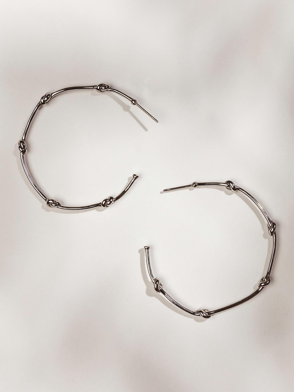 Hoop earrings on a white surface with knots  in the earrings.