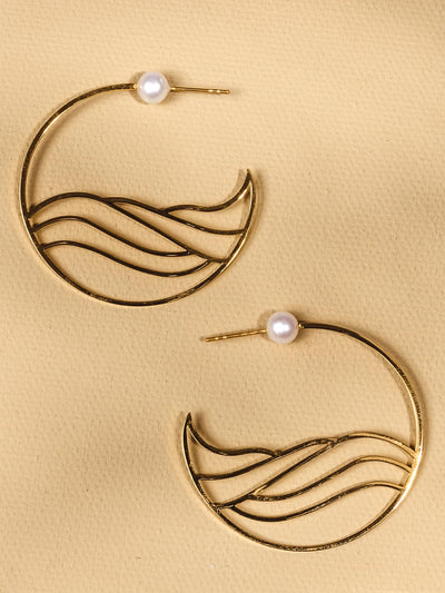 Golden hoops with water-like design in =side the hoop complete with pearl stud on a tan background.