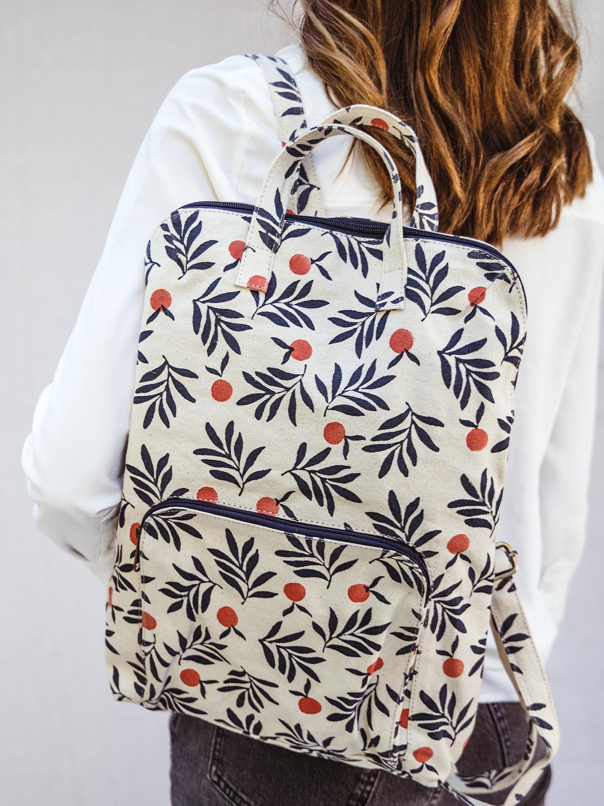 Female model wearing berry pattern backpack over one shoulder.