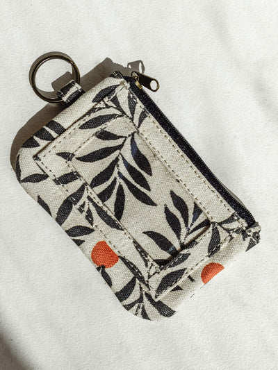 Berry print ID pouch on white surface with zipper and ring to attach.
