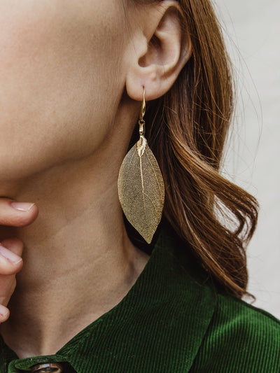 Female models wear golden leaf earrings.