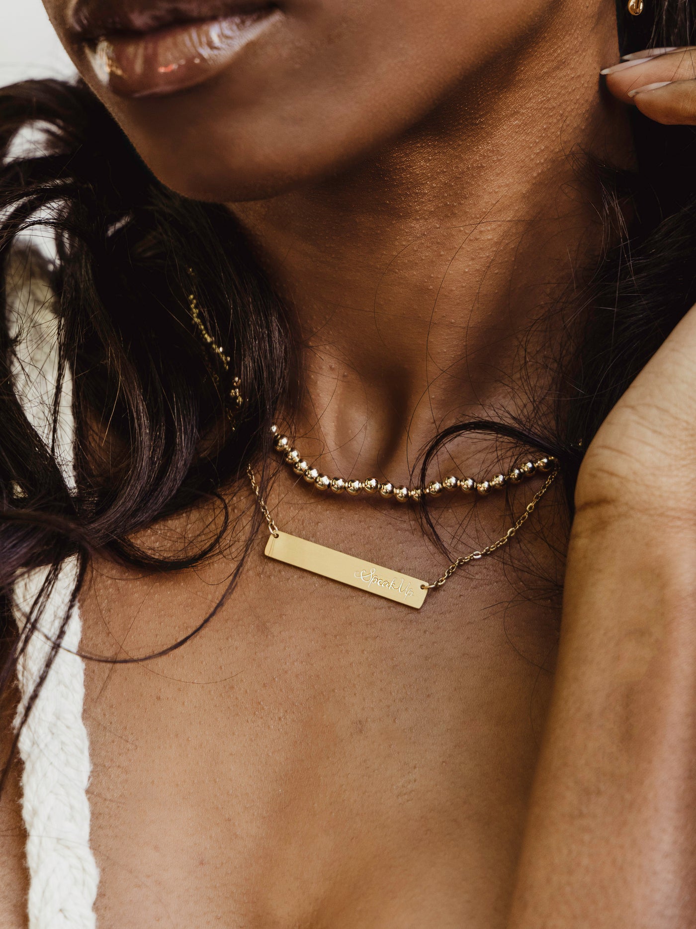 Model wears gold speak up necklace with gold chain and rectangle bar pendant that reads "Speak Up"