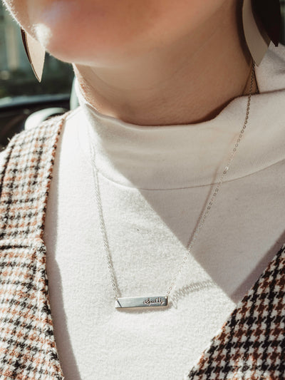 Model wears silver speak up necklace with silver chain and rectangle bar pendant that reads "Speak Up"