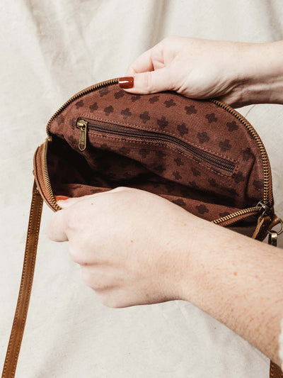 Interior of half-moon hang bag contains quality brown patterned fabric with zipper for extra storage.