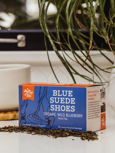 Organic Wild Blueberry Tea box on counter with coffee cup and greenery.