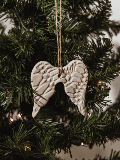 Ceramic angel wing ornament hanging in holiday tree