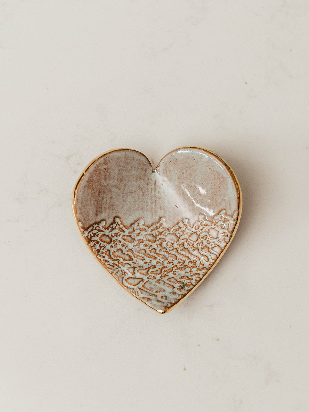 Ceramic heart shaped ring dish with semi texture on white table 