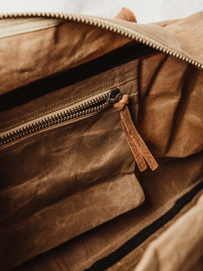 Details of tan weekender bag's internal zipper for additional storage.