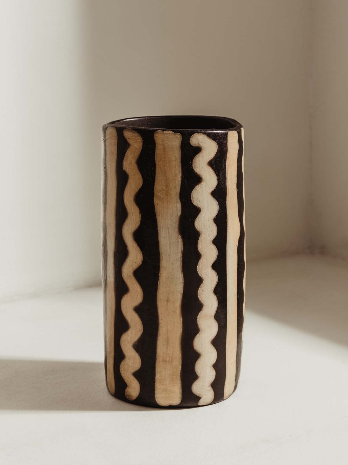 Tall black and white vase with abstract line pattern in white.