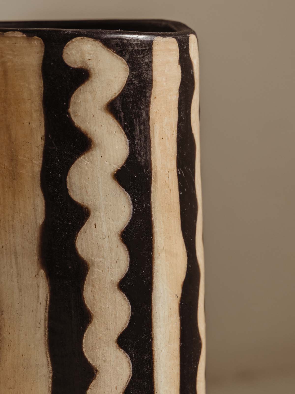 Detail of tall black and white vase with abstract line pattern in white.