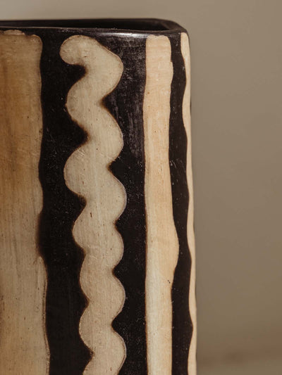 Detail of tall black and white vase with abstract line pattern in white.