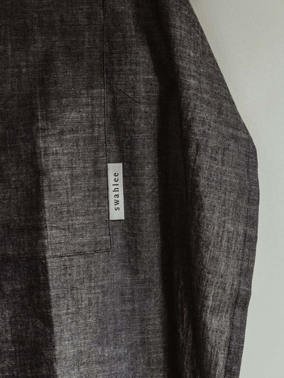 Swahlee Tag on the Gray Apron for Kitchen Grey kitchen apron hangin on the wallCloth dark grey apron hanging on white wall