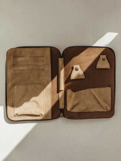 Open light and dark brown leather travel case with storage pockets 