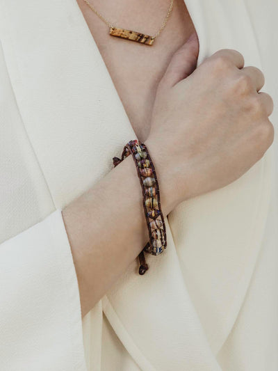 Paper bead pull bracelet on female model wearing a white blazer