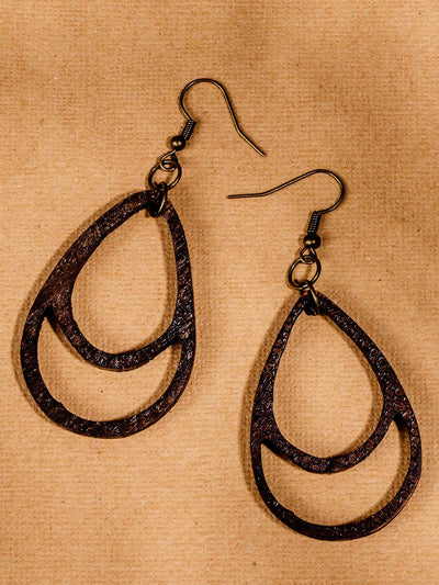 dark brown wooden teardrop earrings on tan table.