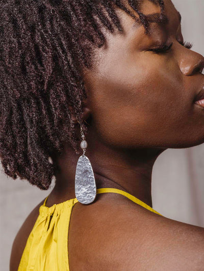 close up of Aluminum earrings on model in a yellow top closing her eyes