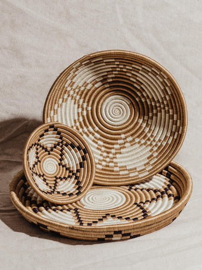 Three woven baskets stacked on top of each other in front of a white background