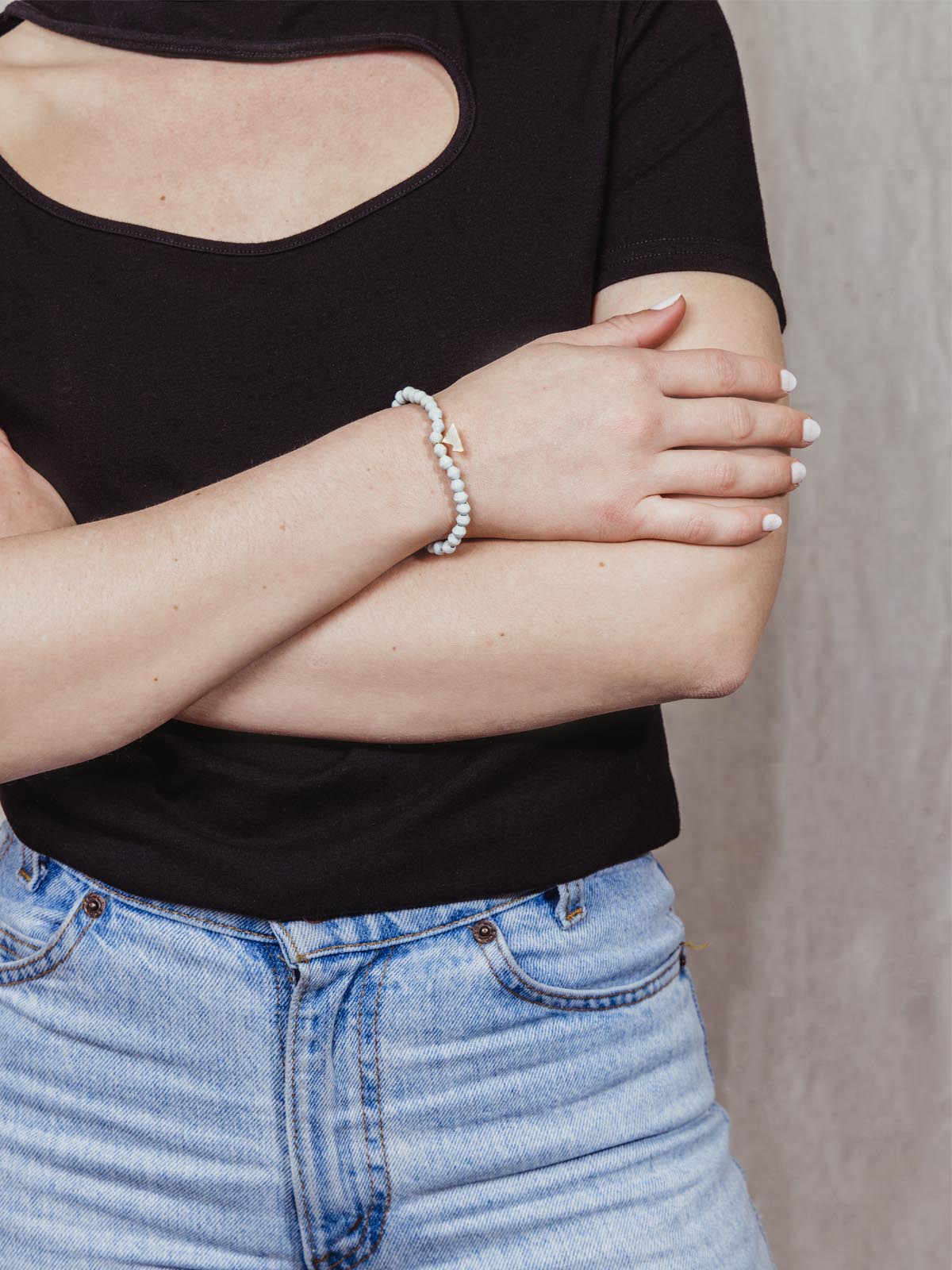 Model wearing pale blue beaded bracelet with golden mountain charm. 
