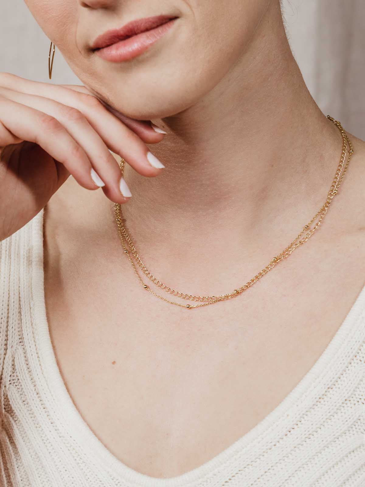 Gold double choker necklace on model with hand on chin