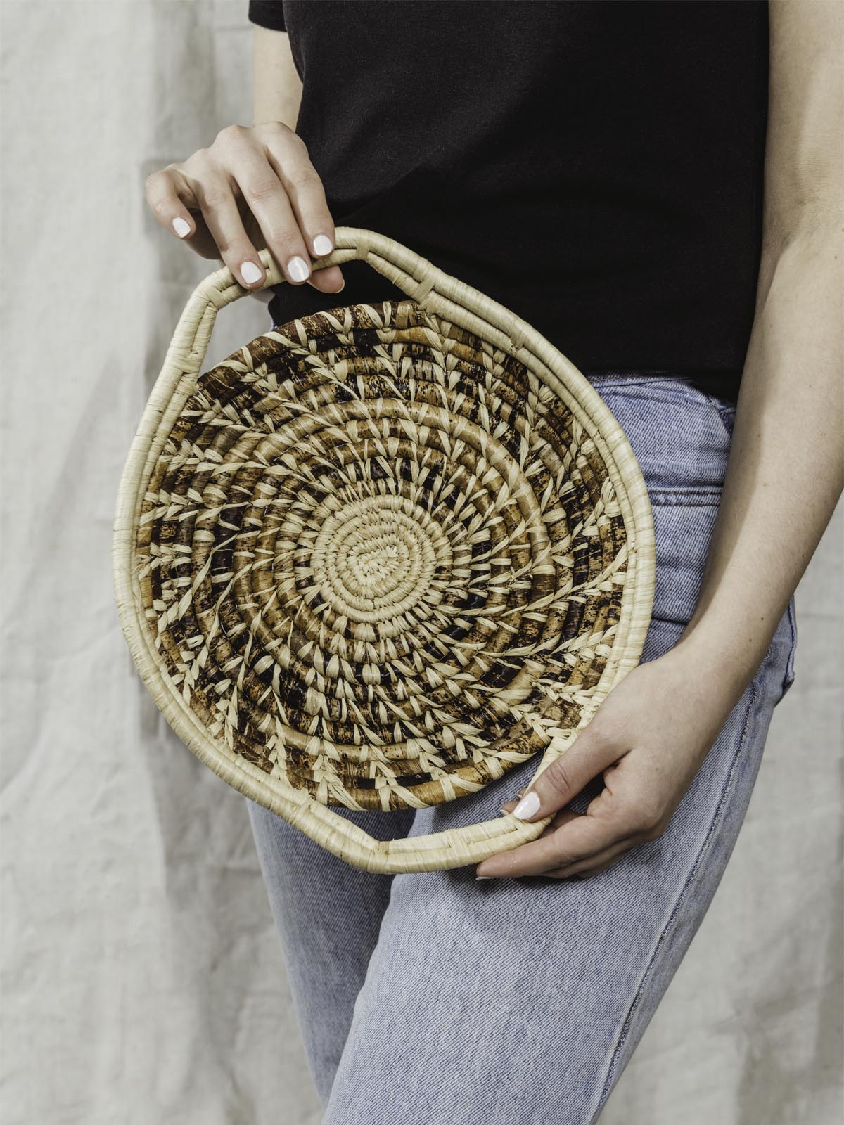 Model holding small brown and tan woven basket with handles