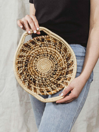 Model holding small brown and tan woven basket with handles