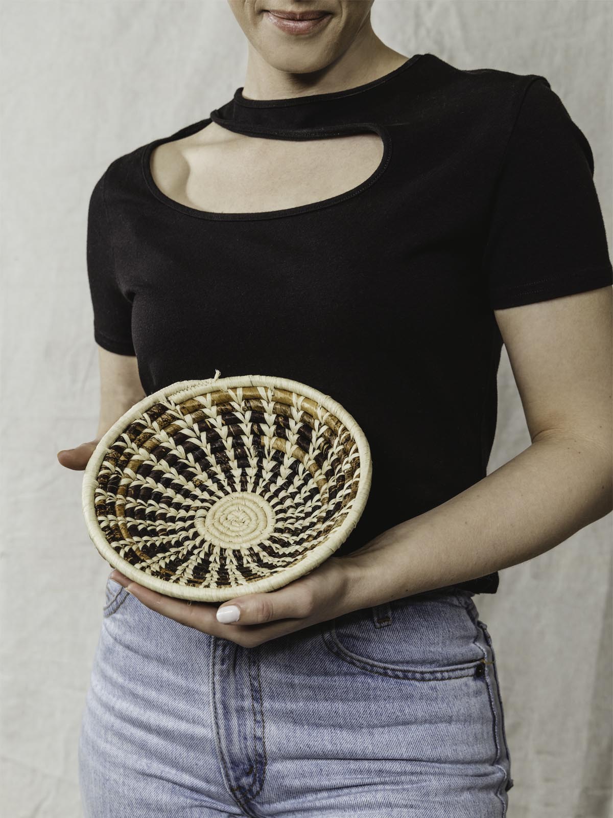 Model holding small brown and tan basket.