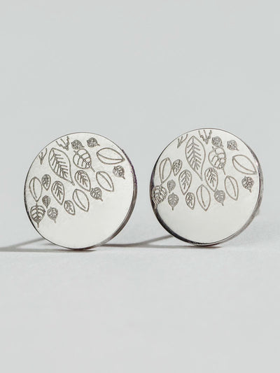 Silver Studs with leave engravings sitting on a white background. 