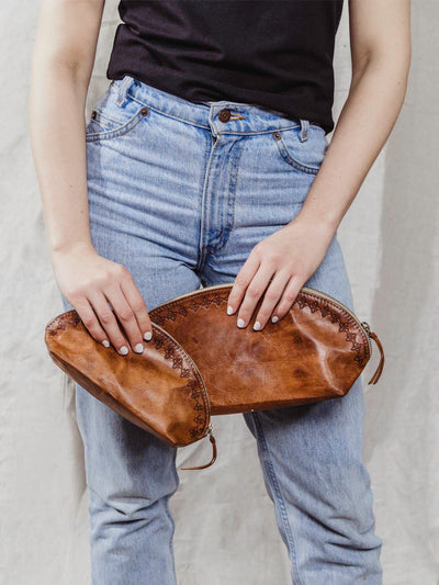 Model holding small and large brown leather pouches