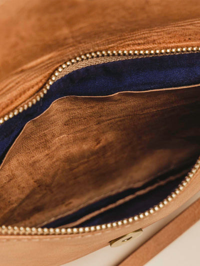 Close up of inside of Brown Leather crossbody clutch on tan background