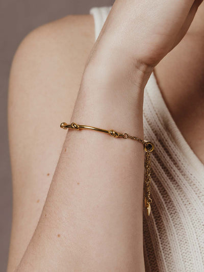 close up of model wearing gold knot bracelet with chain