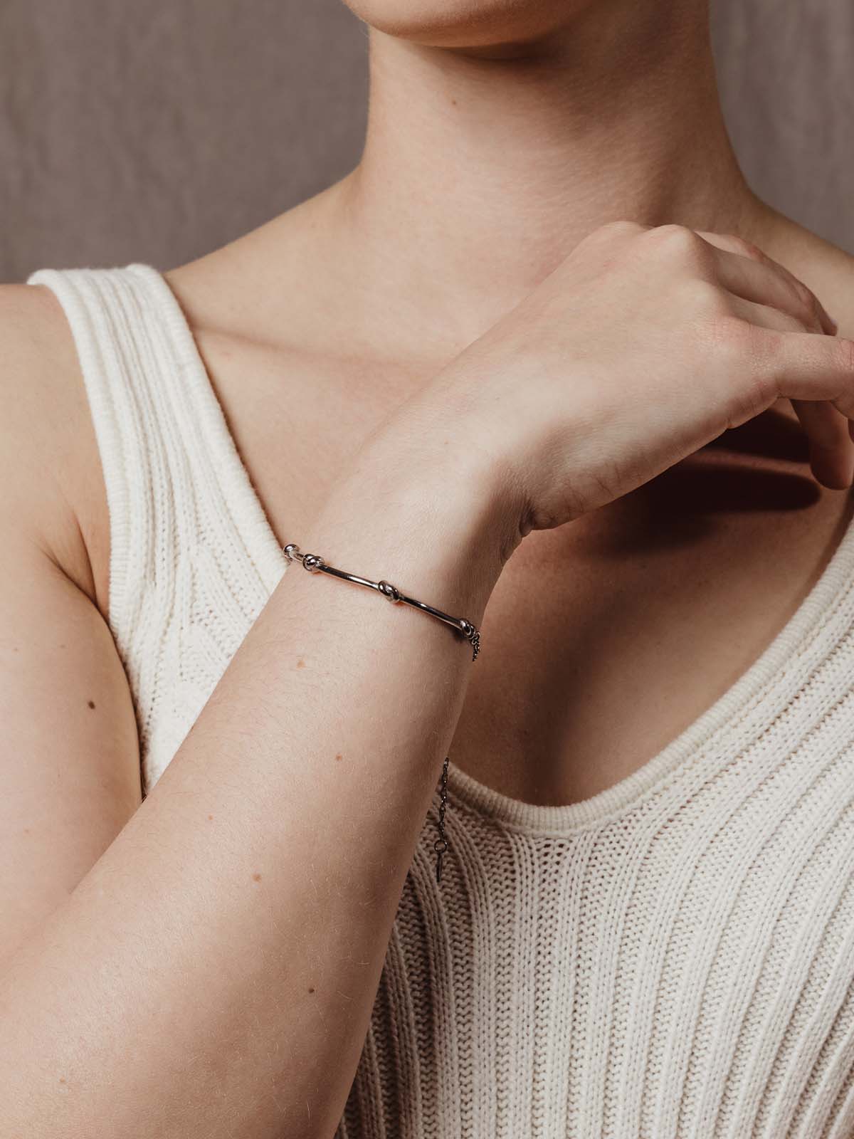 close up of model wearing silver knot bracelet with chain