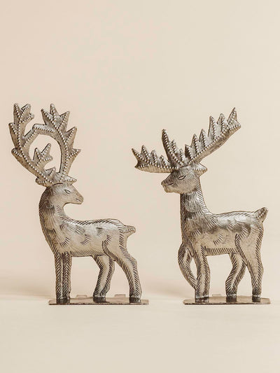 Two Silver raindeer standing on a beige background. 