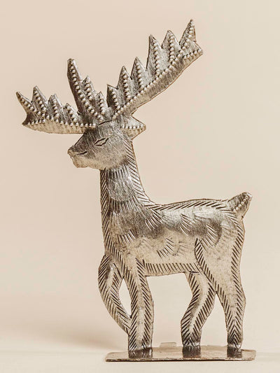 Silver reindeer standing on a beige background. 