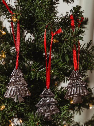 Set of three holiday tree ornaments hanging in a tree. 