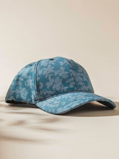 Teal Hat with light floral design on tan background. 