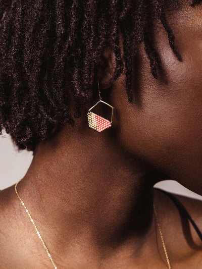 Pink and gold geometric earrings worn on model. 