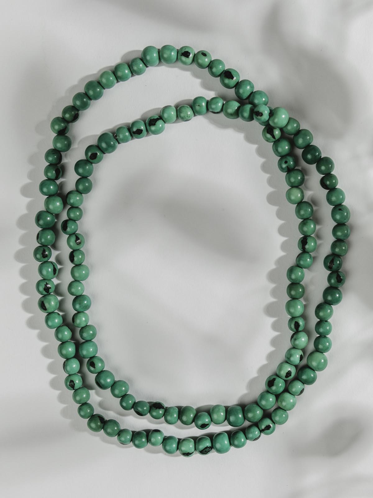 Turquoise necklace laying on a white surface.