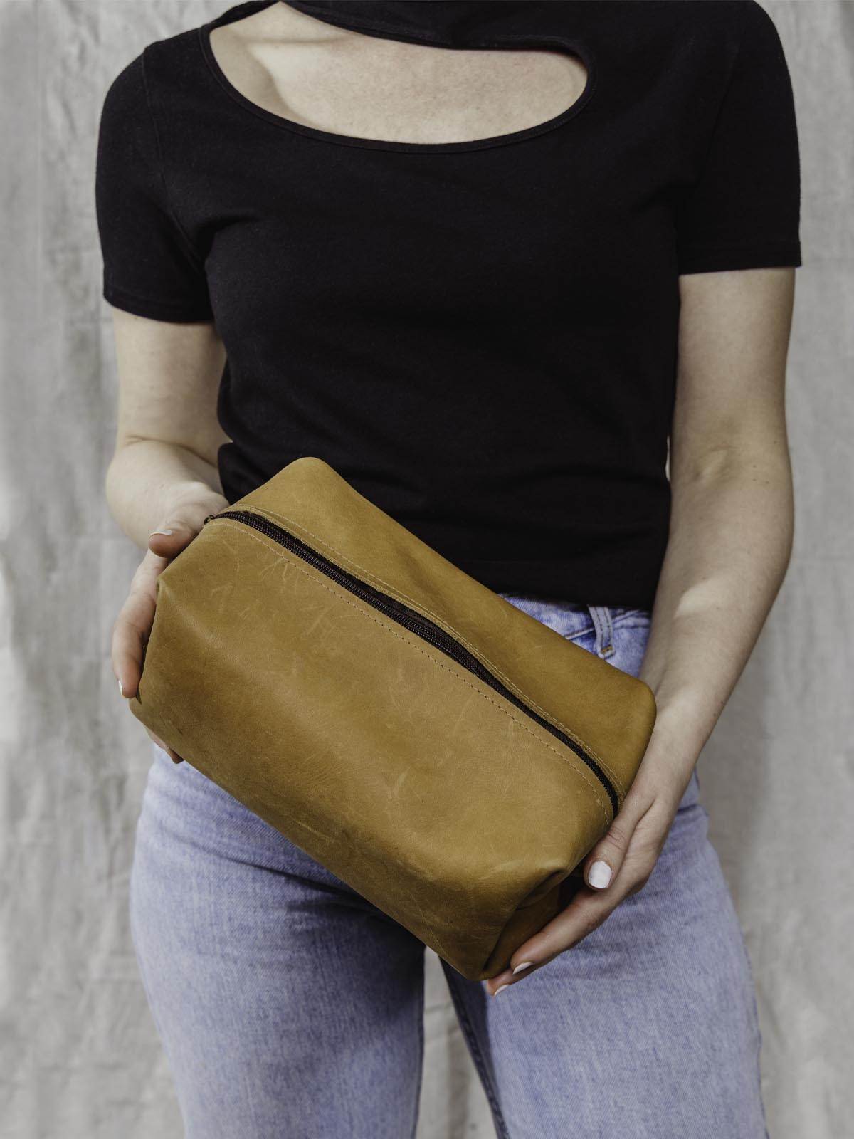 Model holding Carmel colored leather bag with zipper 