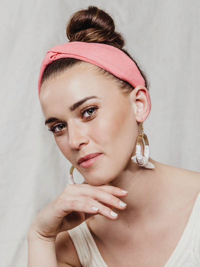 Model wearing coral pink cloth headband.