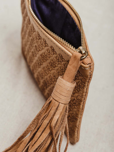 Close up of leather tassel and zipper and cloth lining on inside of pouch. 