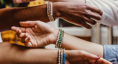 Three women's arms with bracelets on them