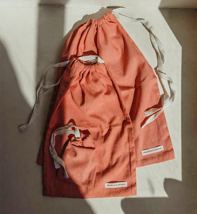 Three coral bags lay in the sun with shadows coming across it