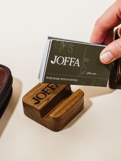 Cell phone used as business card holder with hands placing business cards in stand.