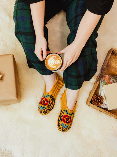 Yellow mustard slocks on a model wearing green plaid pans hold holding a  coffee mug