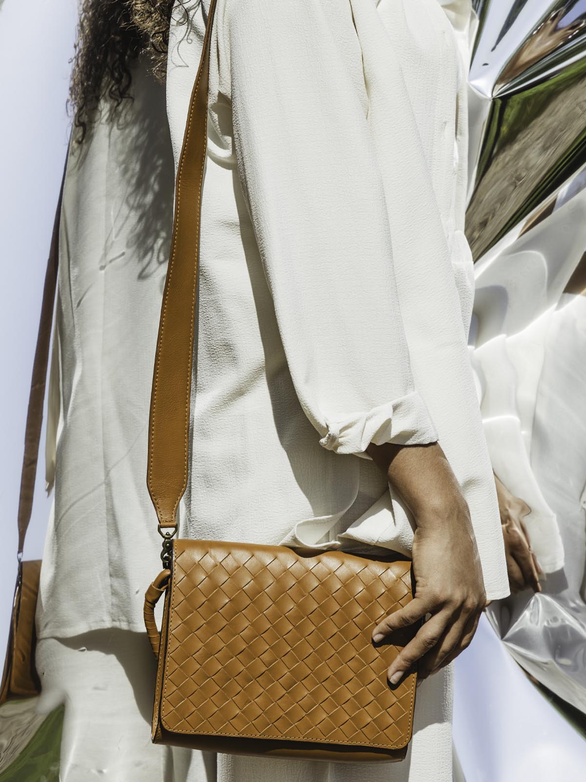 Model with handmade braided leather hand bag over the shoulder. 