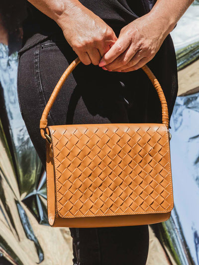 Model with handmade braided leather hand bag  holding it from clutch strap.